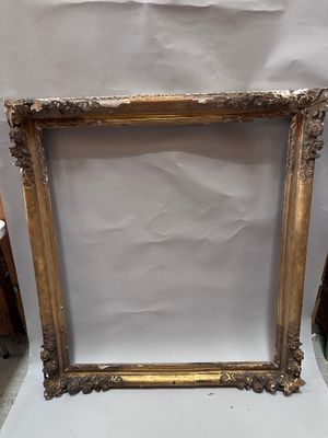 an old picture frame sitting on top of a table next to a chair