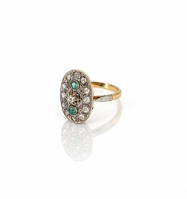 un gros plan d'une bague sertie d'un diamant et d'une émeraude