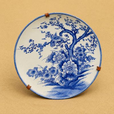 une assiette bleue et blanche décorée d'un arbre et de fleurs