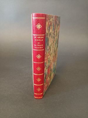 a red book with gold trim sitting on a table