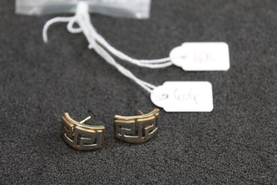 two pairs of gold earrings with tags on them on a table