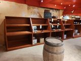 un tonneau en bois posé devant une étagère remplie de bouteilles de vin