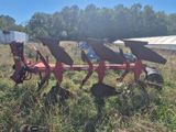 une charrue rouge qui est posée dans l'herbe
