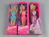 three barbie dolls are in a pink box on a table