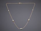 a gold necklace with pearls on a chain on a gray background