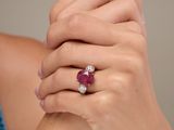 close up of a woman ' s hands holding a ring with a ruby and diamond