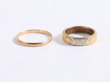 two gold wedding rings on a white surface
