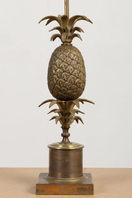 brass pineapple table lamp on a wooden base with a white background