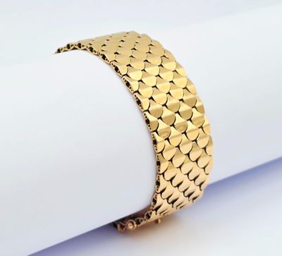 un gros plan d'un bracelet en or posé sur une serviette