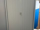 une armoire blanche avec une porte et une poubelle bleue à l'arrière-plan