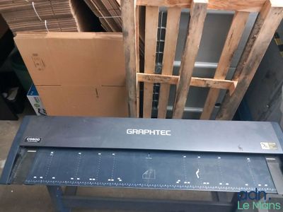 une table sur laquelle est posée une règle, devant une pile de cartons