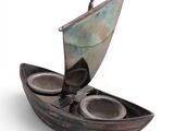 a metal boat with two cups in it on a white surface