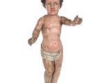 une vieille statue en bois représentant un bébé portant une couche et un pantalon de protection