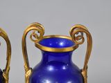 two blue vases with gold handles sitting on a table
