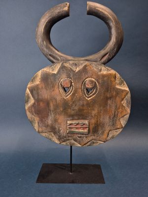 a wooden mask with horns on a stand on a blue background