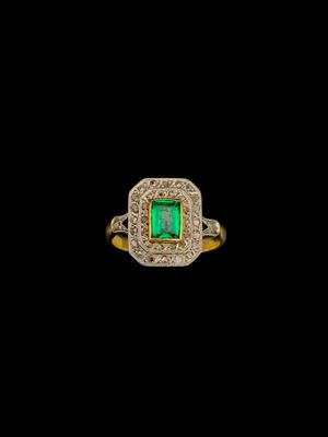une bague sertie d'une émeraude et de diamants sur fond noir