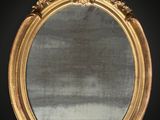 une image représentant un miroir à cadre doré accroché à un mur noir