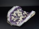 un gros plan sur un morceau de roche violette et blanche posé sur une surface noire