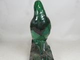 a green bird sitting on top of a marble block