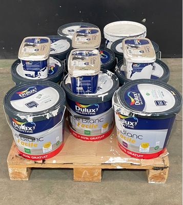 plusieurs seaux de peinture posés sur une palette devant un mur