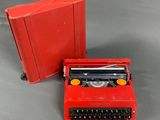 a red typewriter next to a red book