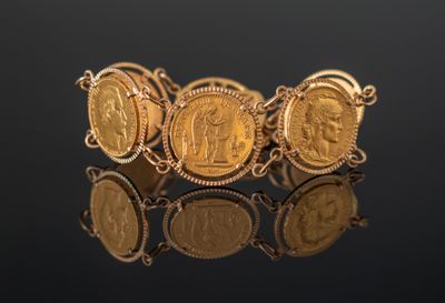 a close up of a bracelet with gold coins on a black surface
