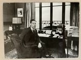 photographie en noir et blanc d'un homme assis à un bureau dans un bureau