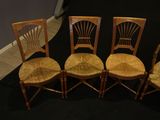 four wooden chairs are lined up against a black backdrop