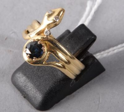 yellow gold ring with a blue sapphire and diamonds on top of a black piece of leather