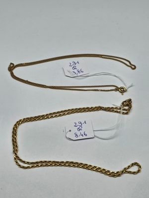 two gold chains with tags attached to them on a white surface