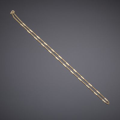 a gold necklace with a long chain on a gray background