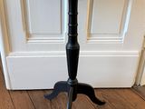 une image représentant une table noire posée sur un parquet, devant une porte