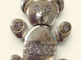 a small silver teddy bear with diamonds on it ' s back