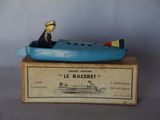 un petit bateau bleu avec un homme à l'intérieur, posé sur une caisse