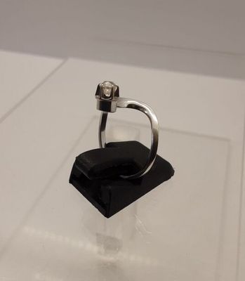 a silver ring on a black stand on a white surface