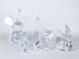 three glass figurines of animals sitting on a white surface