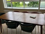 une table avec quatre chaises et une télécommande devant une fenêtre