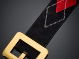 un gros plan sur une ceinture noire et rouge dotée d'une boucle dorée