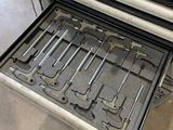 many tools in the drawer of an oven in the kitchen