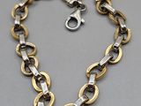 a close up of a gold and silver necklace on a gray surface