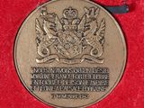 a gold medal on a red cloth with a black ribbon