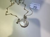 une horloge en argent, entourée d'une chaîne, posée sur une table