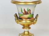 a gold vase with a painting on it on a stand