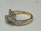 a gold ring with a diamond on it on a white surface