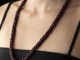 a woman that is wearing a necklace with a red bead