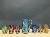 sept verres et un pichet posés sur une table