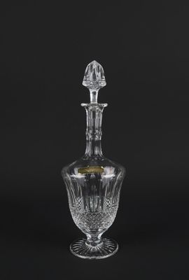 a crystal decanter with a stopper on a black background
