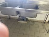 two sinks in a public restroom with a person taking a picture