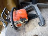 a chainsaw that is sitting on the floor next to a chair