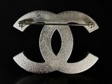 a close up of a silver brooch with a black background